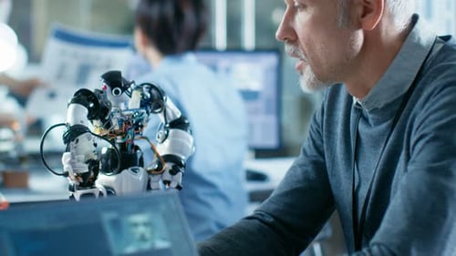 Robotics Engineer Manipulates Voice Controlled Robot, Laptop Screen Shows Speech and Face Recogniti