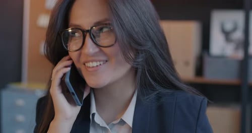 Smiling Professional Woman Making Friendly Phone Call Talking to Business Contact in Office