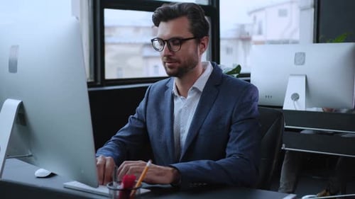 Professional Man Engaged in Working on a Computer in a Contemporary Modern Office Environment