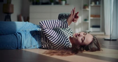 Woman Lies on Floor Using Cell Phone, Smiling