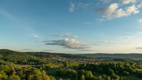 Bewegender Zeitraffer eines Sonnenuntergangs über bewaldeten Hügeln und Dörfern.