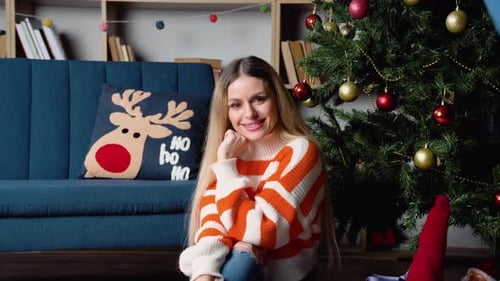 Woman Smiles Next to Christmas Tree Indoors