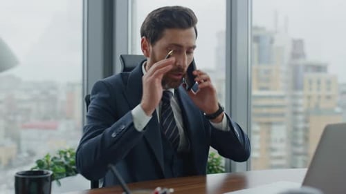 Annoyed businessman arguing on phone feeling stress at work desk in modern office