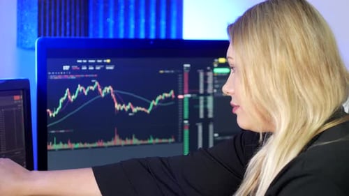 Woman Smiling at Stock Market Data on Computer