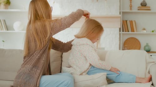 Woman Brushing Child's Hair on Sofa