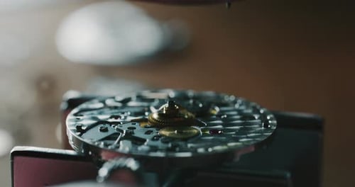 Slow motion close up of a professional watchmaker repairer working on a luxury mechanism watch gea