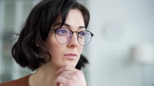 Thoughtful Woman with Glasses Resting Chin on Hand