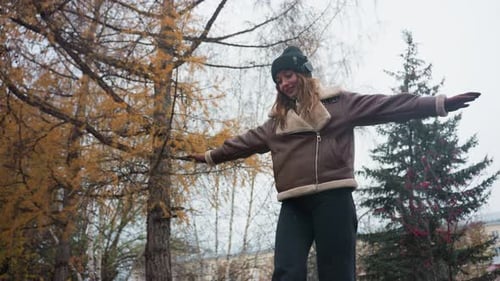 Happy Girl Balancing Gracefully on Stone Wall in Autumn Park