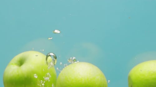 Grüner Apfel, der in kochendes Wasser fällt, frisch geschnittenes Obst und Gemüse, das ins Wasser spritzt
