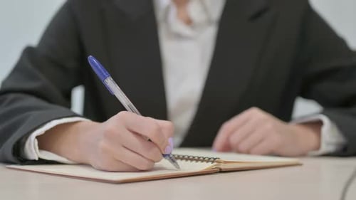 Close Up of Young Businesswoman Writing at Work