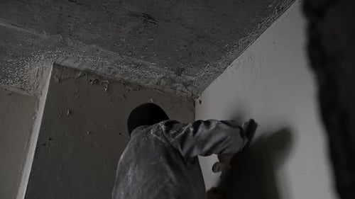 Man Smoothing Wall with Tool in Unfinished Room