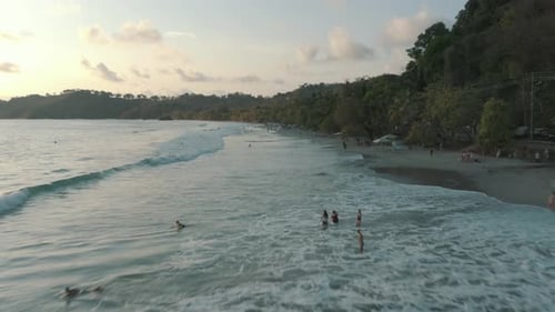Zumbido aéreo sobrevolando la playa durante las vacaciones de verano con gente jugando con las olas