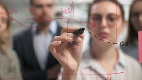 Woman Drawing Graph with Colleagues in Office