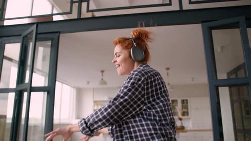 Woman with Headphones Dancing Happily in Apartment