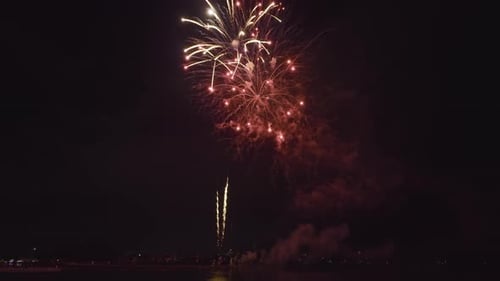 Vista aérea de fogos de artifício brilhantes explodindo com luzes coloridas sobre a costa do mar no Dia da Independência dos EUA