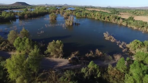 Aerial shot of a big industrial truck loading gravel on a road in the middle of wetlands in Sonora