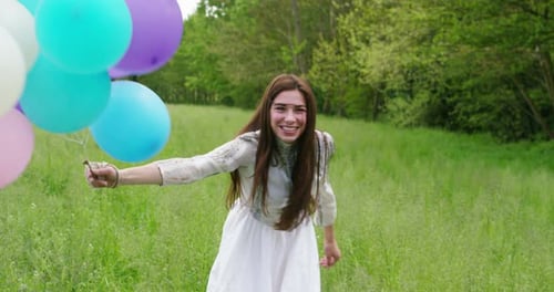 Woman Runs Through Field Holding Balloons