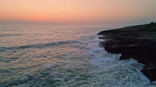 Pastel Sunrise Splashing Ocean Aerial View. Foamy Waves Washing Stoned Seashore At