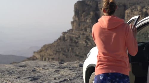 Young woman steps out of car to admire beautiful canyon landscape view