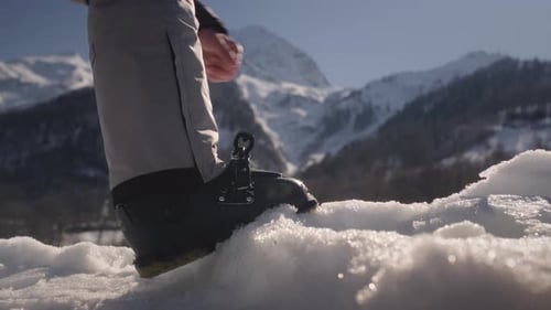 Le skieur met son pied avec des chaussures de ski et attache la fermeture en ajustant la boucle de la chaussure