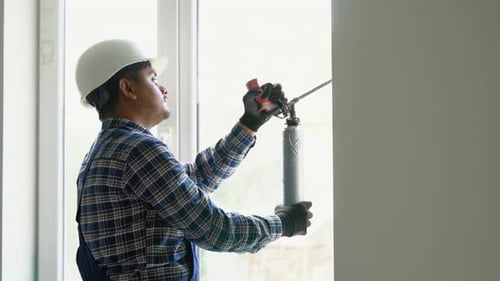 Construction Worker Sealing Window Frame with Foam