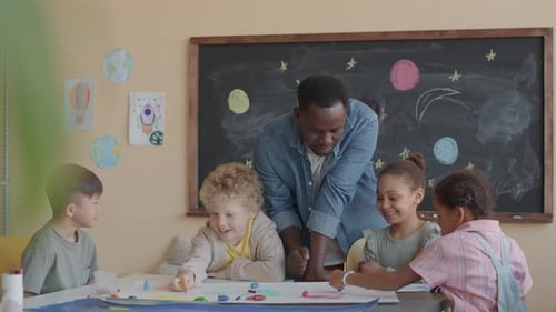 Teacher Helps Diverse Children with Art Project
