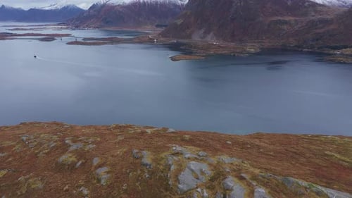 Flying from land over a fjord in Norway near Lofoten. Beautiful scenery of the landscape with snow c