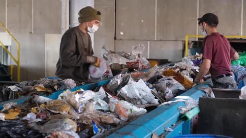 Workers Sorting Garbage Moving Down The Belt At A Recycling Plant