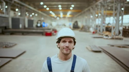 Porträt eines Industriearbeiters mit Schutzhelm und Overall, der in einer Fabrik steht