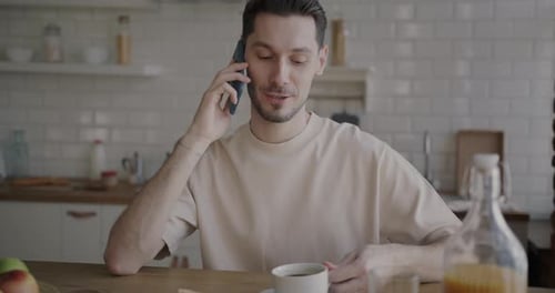 Man Talking on Phone While Having Coffee Indoors