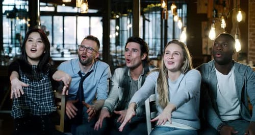 Slow motion of happy three college friends drinking beer and cheering together in a pub. Shot in 8