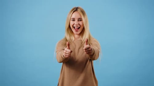 Positive Woman Makes Thumbs Up Gesture Showing Approval