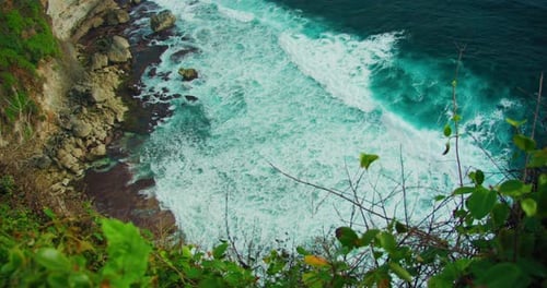Rocky Coastline with Turquoise Shallow Ocean Water Waves Foaming and Crash on Cliff