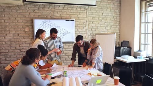 Group of young business people discussing architectural designs in office.