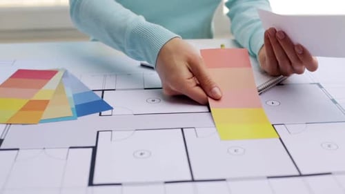 Woman choosing interior colors with house blueprint in architectural design business