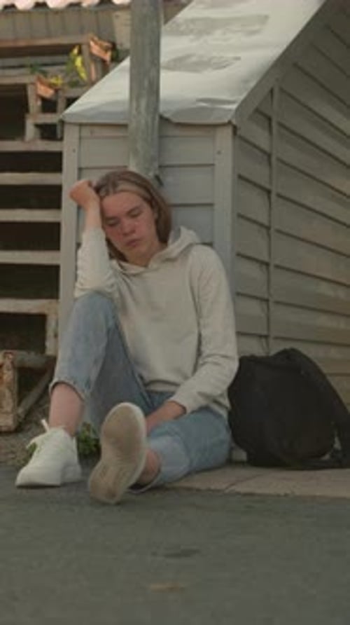 Young Woman Seated in Thoughtful Pose By Stadium Walkway