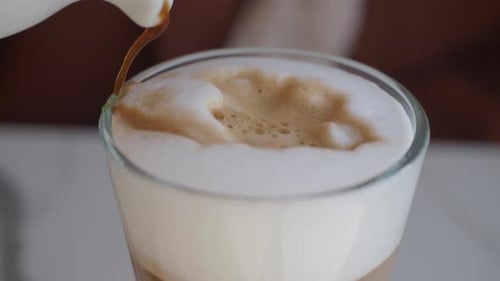 Stream of Coffee Pouring into Foamy Glass