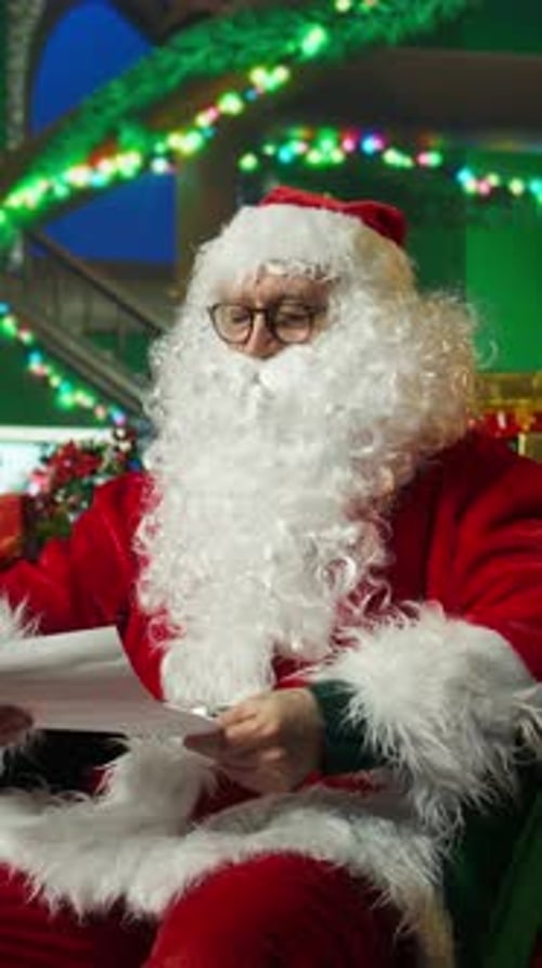 Retrato de vídeo vertical de homem sorridente vestido de Papai Noel acenando com a mão cumprimentando crianças