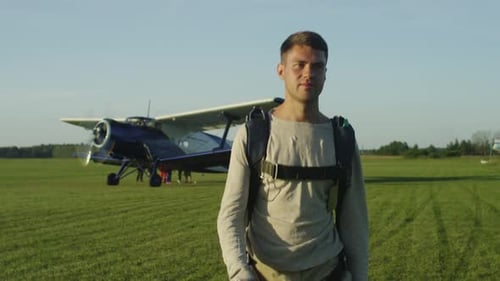 Young Adult Man Walking on Airfield with Biplane