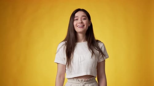 Young Woman Smiling and Winking on Yellow Background