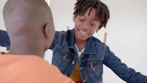 Happy african american father and son embracing at home, slow motion