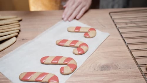 The woman is making homemade gingerbread cookies and decorating them with icing.