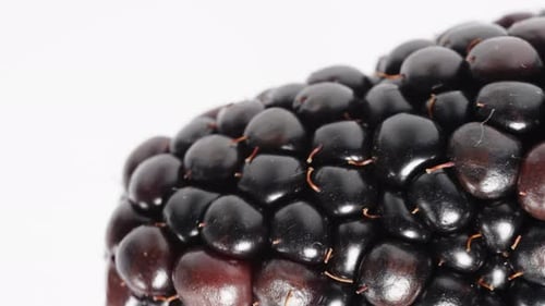 In macro view, a blackberry rotates on a white background.