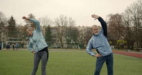 Couple of Senior People Exercise Outdoors on a Stadium