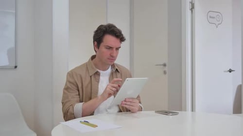 Man Receives Bad News on Tablet in Office