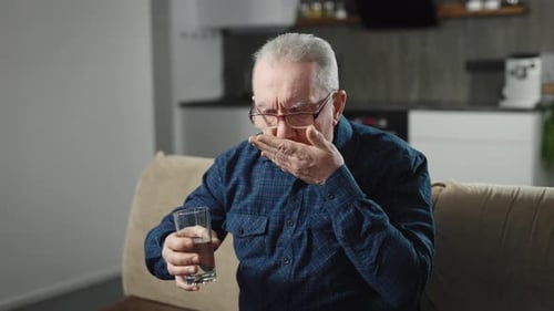 Senior Man Taking Pills with Water at Home