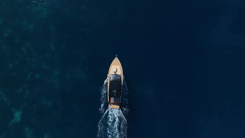 Barco navegando por el mar azul abierto - Seguimiento aéreo de arriba hacia abajo - Dolly Out