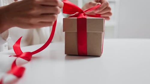Close Up Female Hands Untie Gift Red Ribbon Bow Falling Box Open, Holiday Gift In Woman Hands