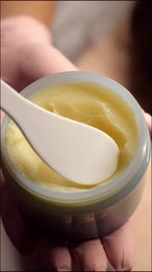 Close-up of Hand Scooping Cream from Jar