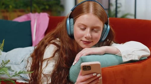 Woman Relaxes on Couch with Phone and Headphones